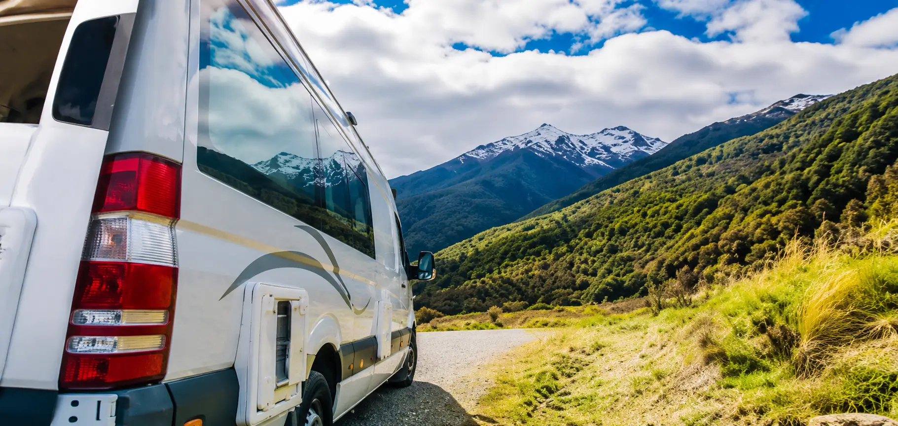 autocaravana Mercedes-Benz Sprinter aparcada en una carretera rural con montañas nevadas